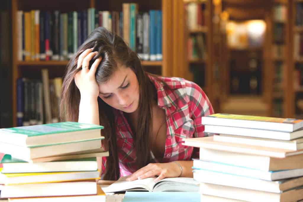 Focused student surrounded by books in a library