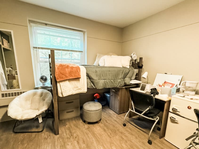 College dorm room with storage hacks like under-bed shelves, storage ottoman, and more.
