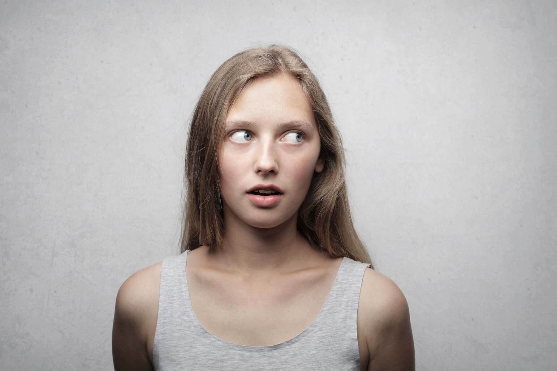 Young woman looking sideways with a curious expression in a studio portrait.